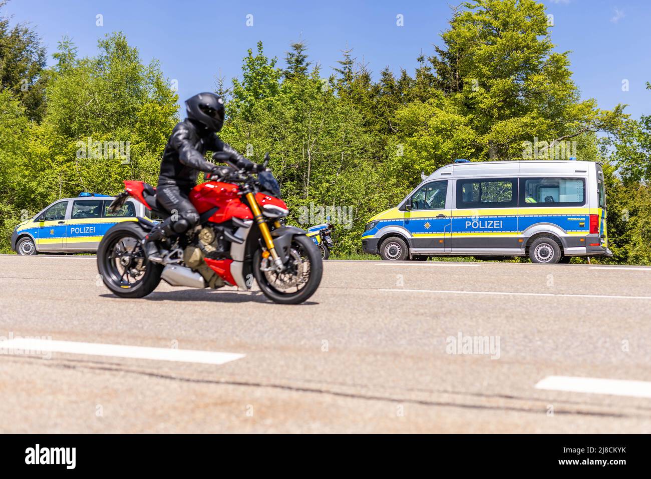 15 maggio 2022, Baden-Wuerttemberg, Pforzheim: Un motociclista passa davanti a un checkpoint della polizia. La sede della polizia di Pforzheim sta effettuando oggi un controllo motociclistico su larga scala sul B500 nel distretto di Freudenstadt. Foto: Philipp von Ditfurth/dpa Foto Stock