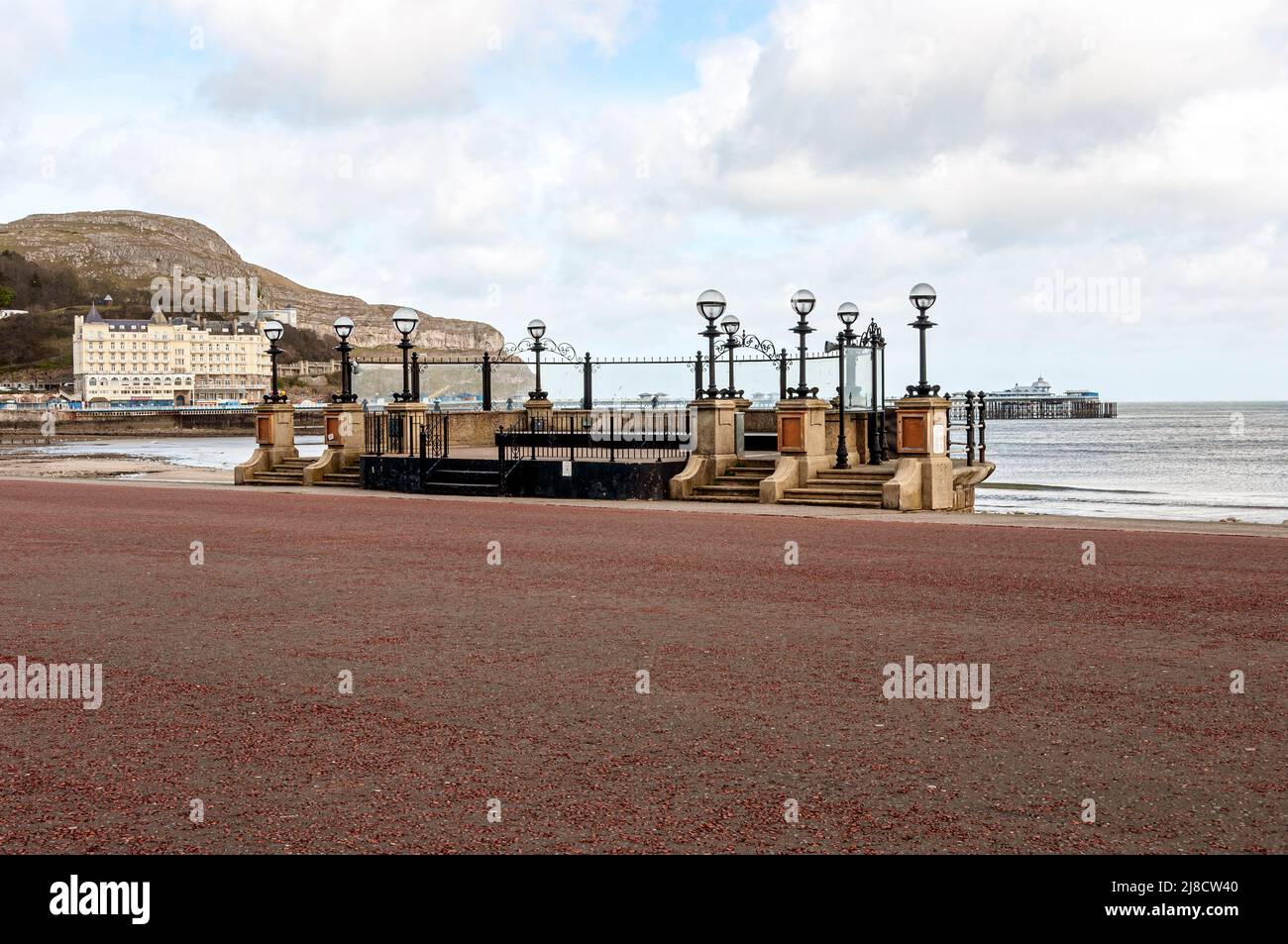 Inizio 20th secolo calcestruzzo ferro e pietra Llandudno bandstand con una parete posteriore semicircolare al podio arredato con lampade in ferro su tre moli Foto Stock