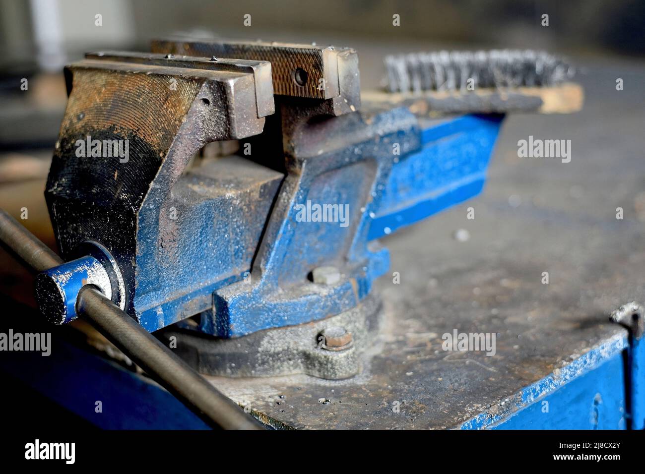 Banco di lavoro in metallo con viscere per il serraggio di parti. Vista del luogo di lavoro in officina. Ordine e pulizia sul luogo di lavoro. Protezione del lavoro. Sfondo Foto Stock