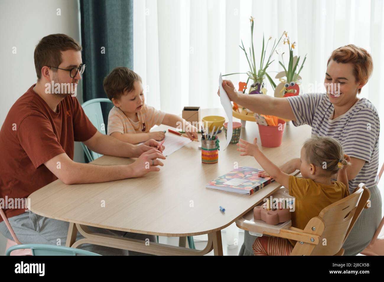 Famiglia con bambini divertirsi a casa al tavolo, creando arte fatta a mano padre e bambini disegno e comunicazione in cucina Foto Stock