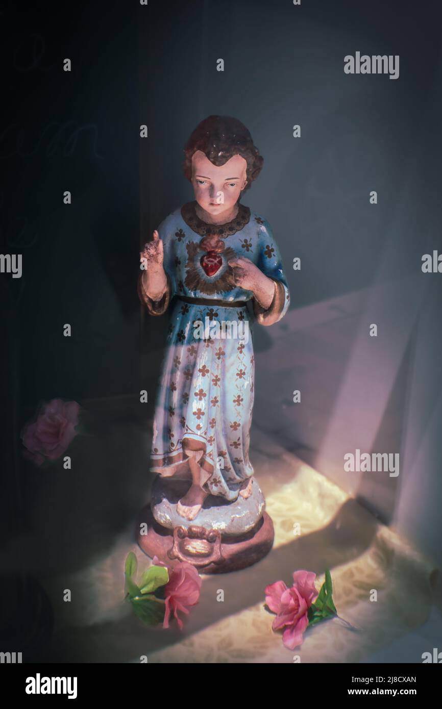 Vintage statua del cuore immacolato di una giovane Maria con luce che scorre dentro e fiori sparsi Foto Stock Vintage statua del cuore immacolato di una giovane Maria con luce che scorre dentro e fiori sparsi Foto Stock