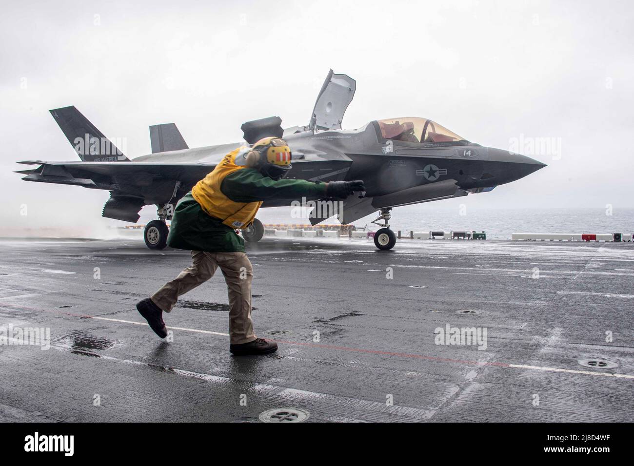 US Navy Chief Aviation Boatswains Mate Akiel Meyers segnala un aereo da caccia del corpo Marino F-35B Lightning II, attaccato ai draghi di Marine Medium Tiltrotor Squadron 265, per lanciare dal ponte di volo della nave d'assalto anfibio di classe americana USS America, 17 gennaio 2022 che opera sul Mare della Cina Orientale. Foto Stock