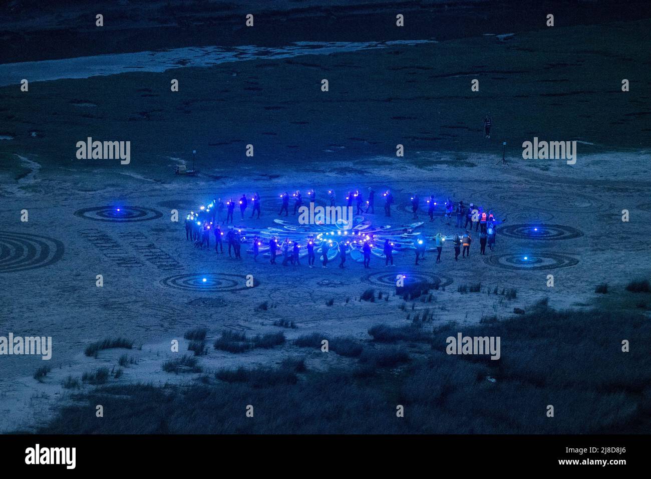 Le persone sono raffigurate in un cerchio su Three Cliffs Bay a Gower, Swansea, mentre prendono parte all'evento Green Space Dark Skies che si tiene nei parchi nazionali e nelle aree di straordinaria bellezza naturale in tutto il Regno Unito fino a settembre. Utilizzando luci a basso impatto tenute da volutieri per creare uno spettacolo di luci, il progetto mira a celebrare la natura, la nostra responsabilità di proteggerla e il diritto di tutti di esplorare la campagna. Foto Stock