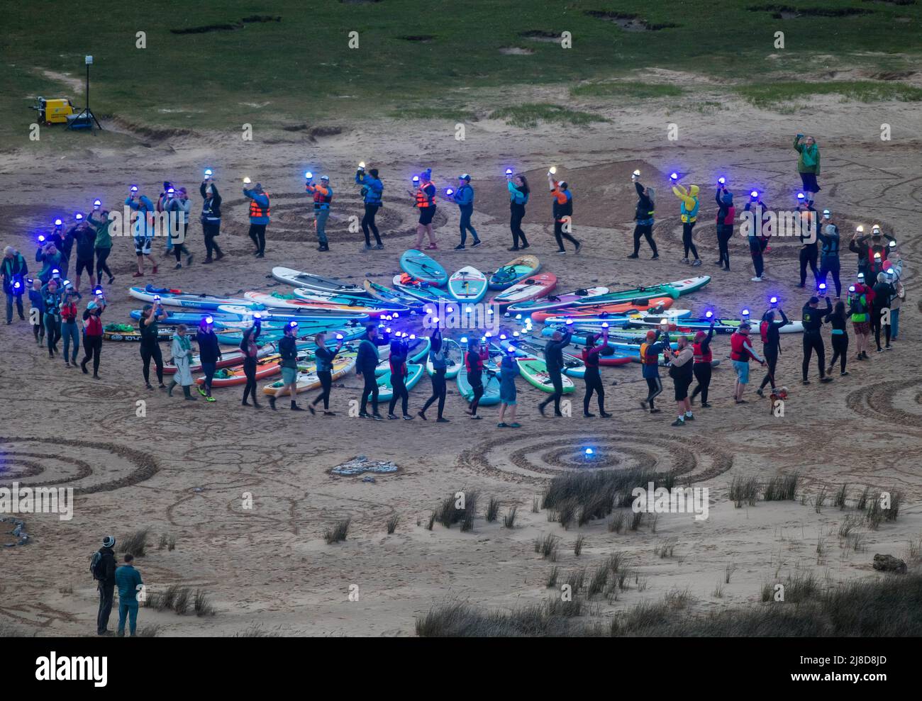 Le persone sono raffigurate in un cerchio su Three Cliffs Bay a Gower, Swansea, mentre prendono parte all'evento Green Space Dark Skies che si tiene nei parchi nazionali e nelle aree di straordinaria bellezza naturale in tutto il Regno Unito fino a settembre. Utilizzando luci a basso impatto tenute da volutieri per creare uno spettacolo di luci, il progetto mira a celebrare la natura, la nostra responsabilità di proteggerla e il diritto di tutti di esplorare la campagna. Foto Stock