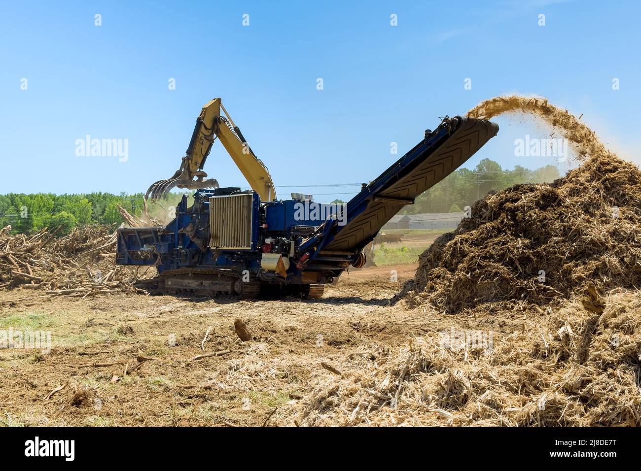 Una gru idraulica di carico per trituratrice in legno di radici Foto Stock