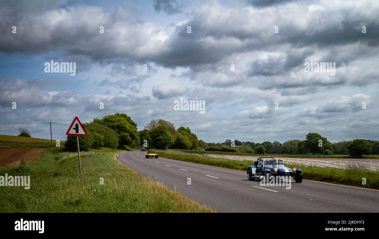Due automobili di Caterham 7 (Lotus 7) di sport guidano in una giornata di sole lungo la campagna inglese A272 strada. Foto Stock
