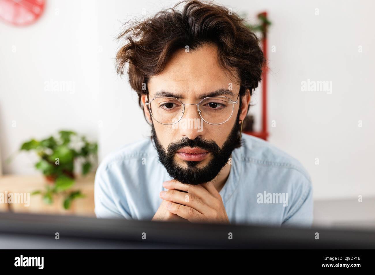 Giovane uomo portico in occhiali di lavoro concentrato sul computer portatile da casa Foto Stock