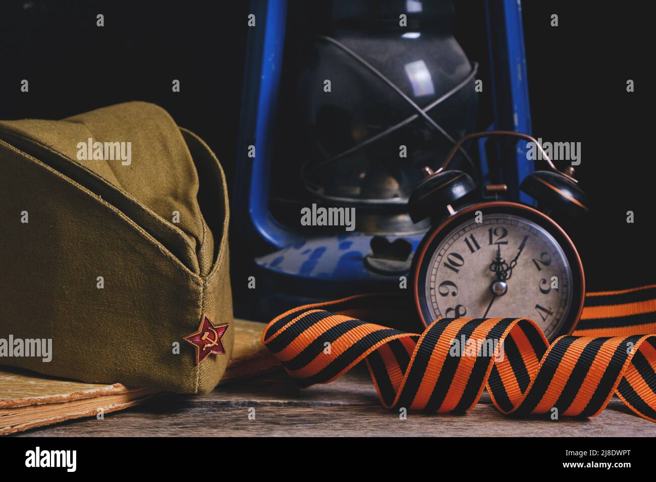 Cappellino soldati russi, St. George nastro, vecchio libro e una sveglia con lampada cherosene. La Giornata della vittoria è il 9th maggio Foto Stock