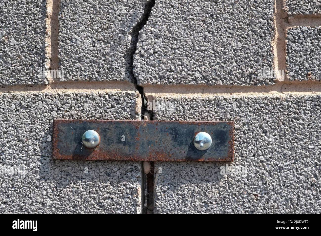 Un muro di cemento incrinato riparato con ironware architettonico. Foto Stock
