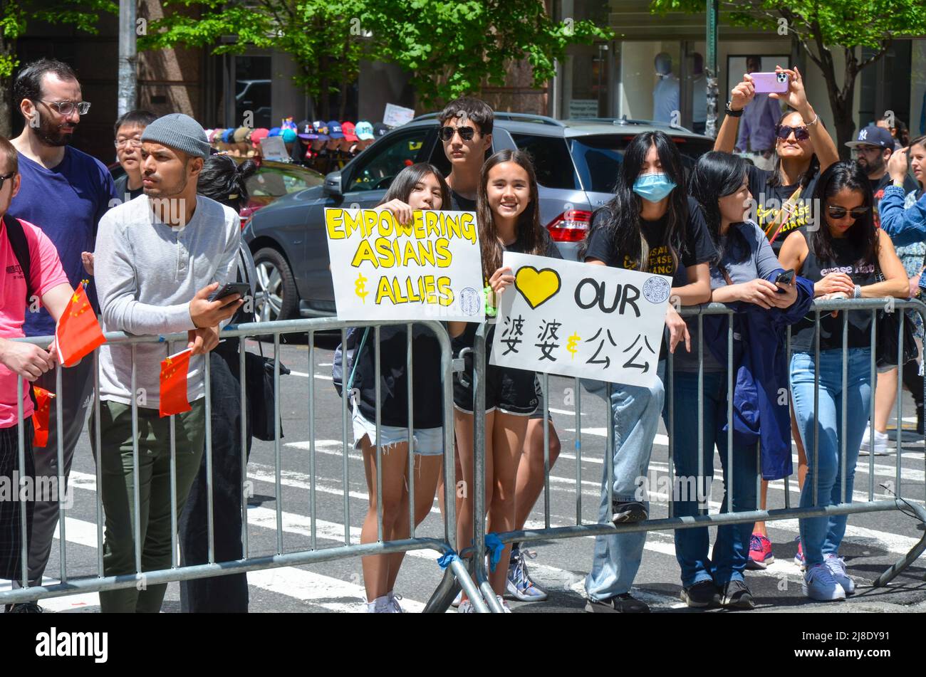 Gli spettatori sono visti tenendo cartelli pro-asiatici sulla Sixth Avenue a New York City durante l'Asian American and Pacific Islander Cultural and Heritage Para Foto Stock