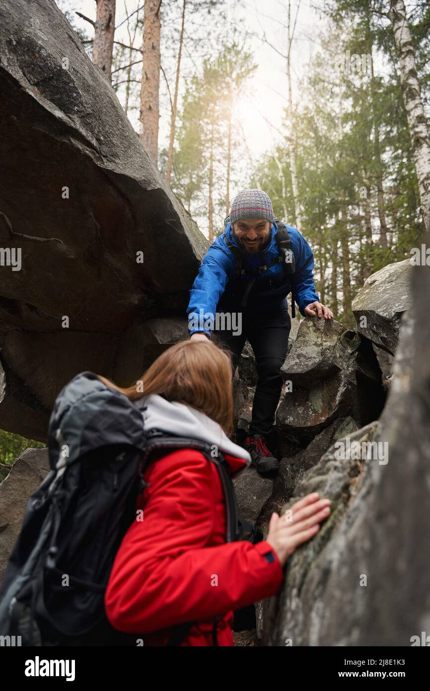 Uomo che presta una mano alla donna durante l'arrampicata su roccia Foto Stock