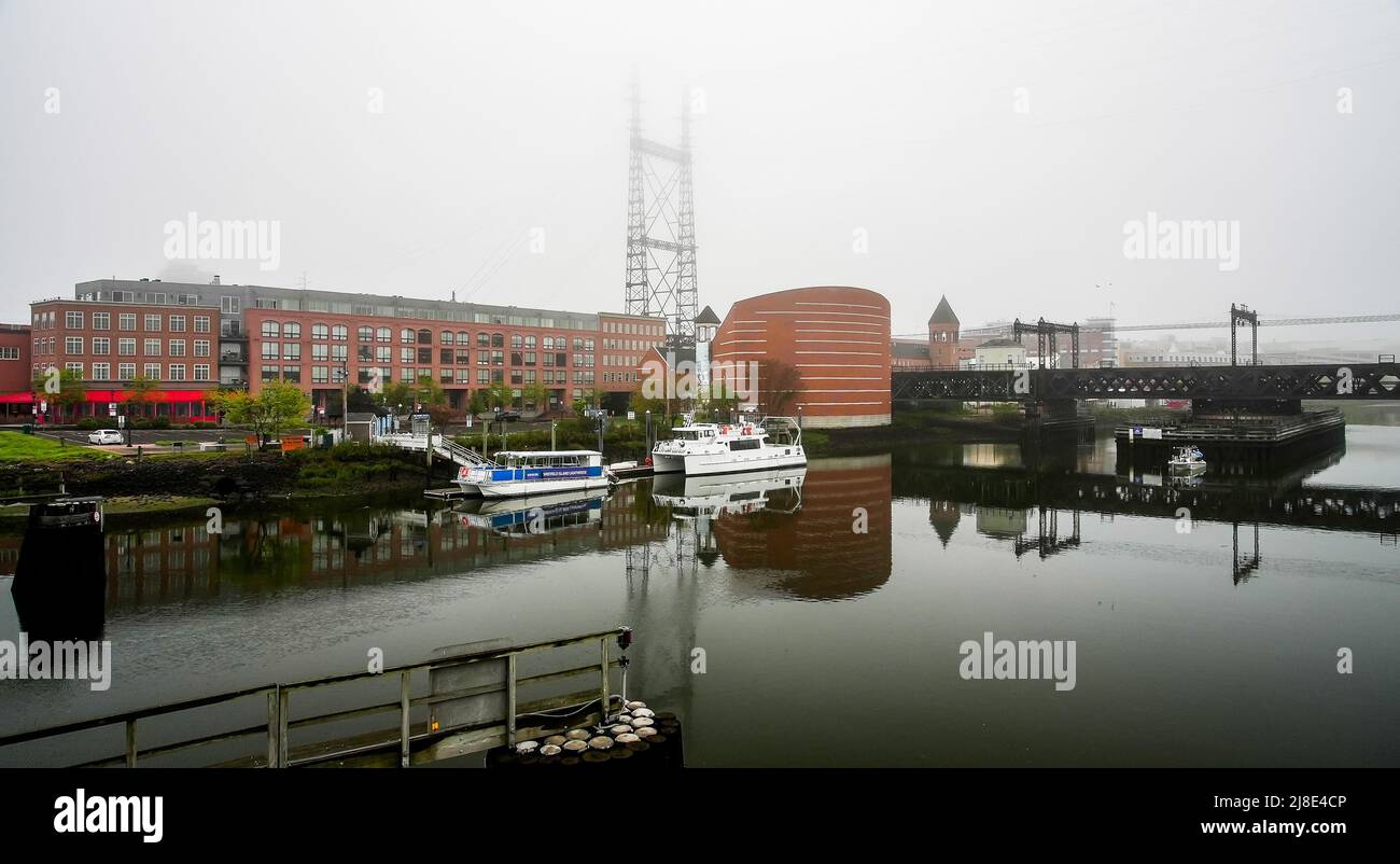 NORWALK, CT, USA - 15 MAGGIO 2022: Bella nebbia mattutina vicino al centro con acquario marittimo, barche e bricge railrod Foto Stock
