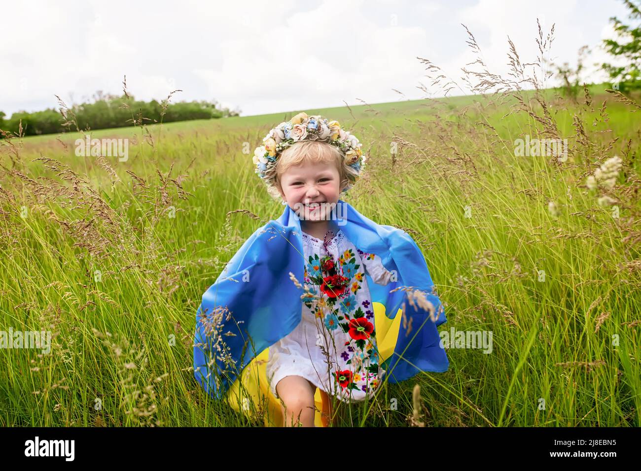 Bandiera di Ucraina nelle mani di ragazza felice ucraino. Bambino sorride indossando bandiera ucraina blu e gialla bandiera di Ucraina svolazzante sul cielo blu backgroun Foto Stock