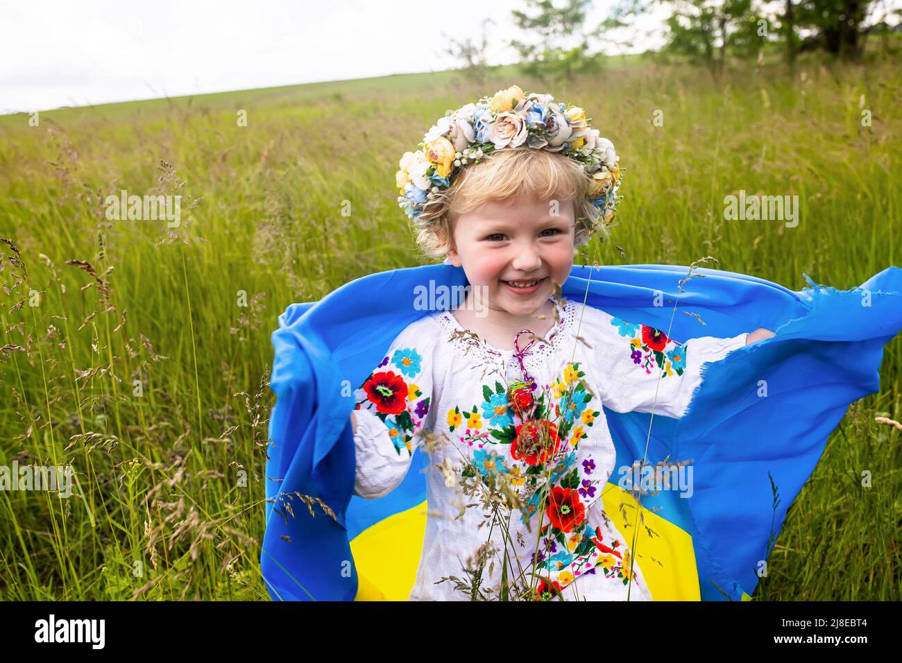 Bandiera Ucraina blu gialla nelle mani della ragazza che corre su campo mangled di grano. Bambino felice con la bandiera dell'Ucraina. Giorno dell'indipendenza. Giorno flag. Const Foto Stock