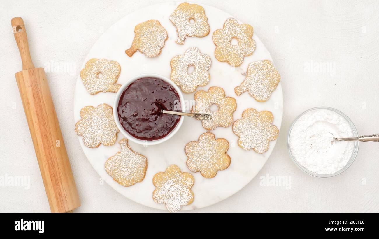 Biscotti a forma di fiore con confettura di lamponi. Foto Stock