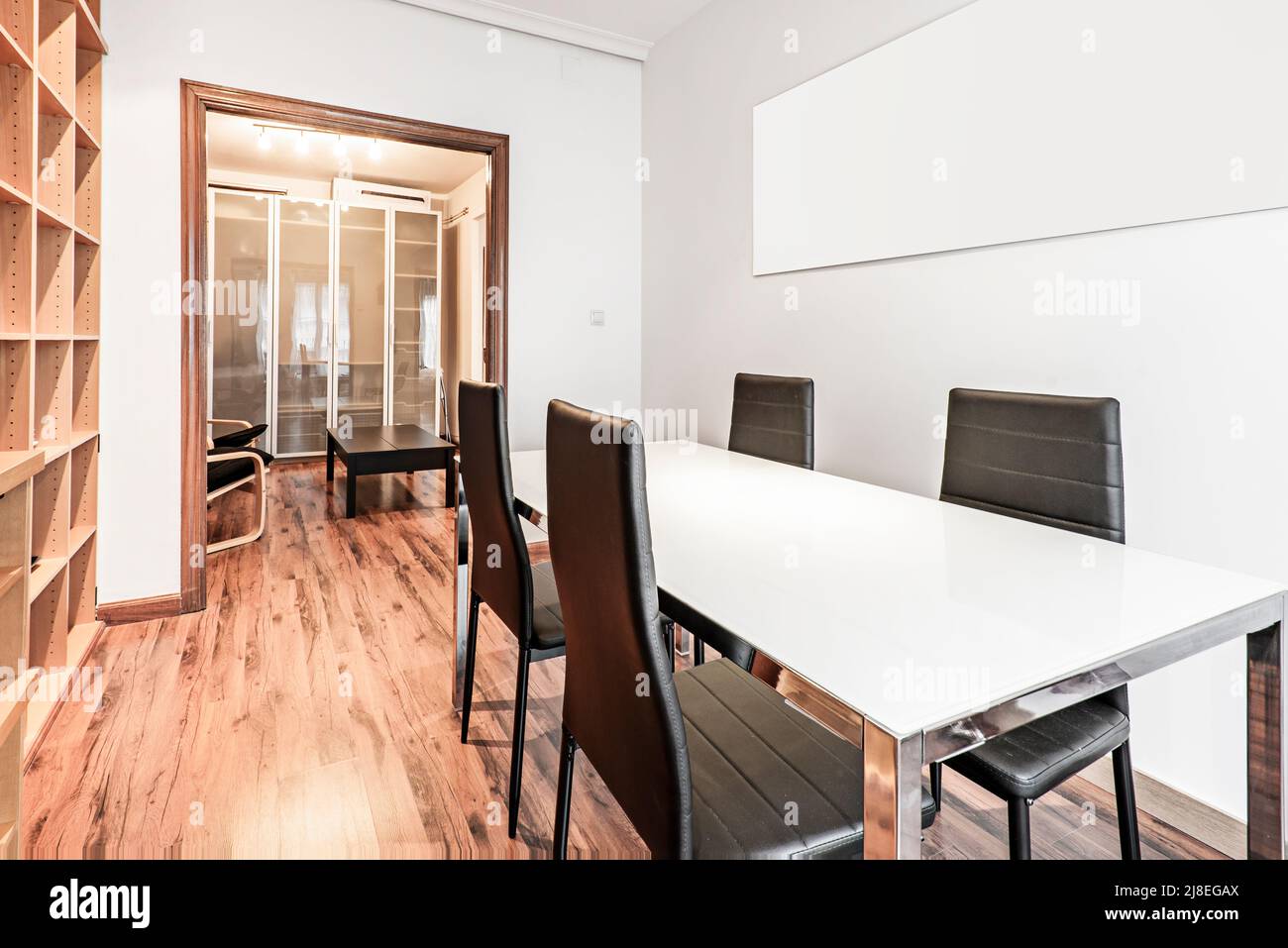 Ufficio con un lungo tavolo in metallo bianco e cromato con sedie a sdraio nere e ripiano in legno Foto Stock