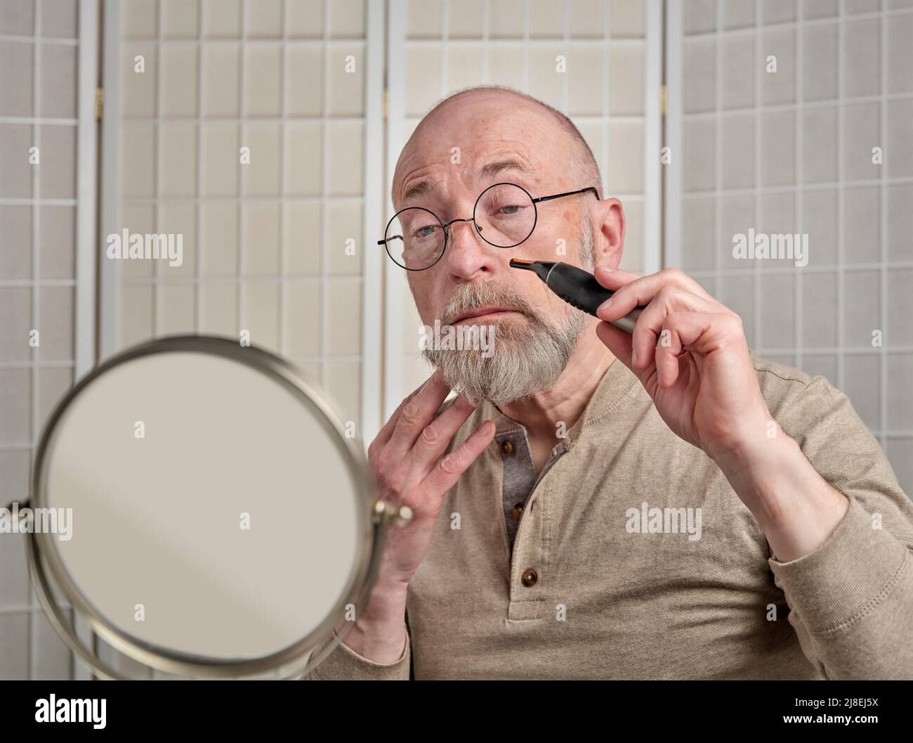 calvo e uomo anziano bearded sta usando il rifinitore elettrico per rifinire i capelli del naso, la cura del corpo e la cura di auto per l'uomo concetto Foto Stock