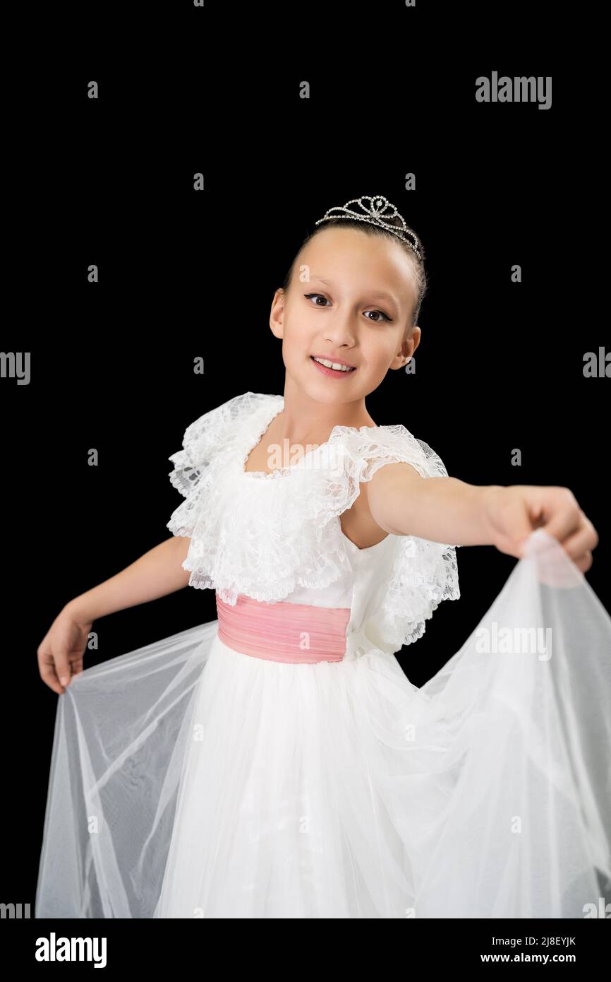 Ballerina sorridente ragazza ballerina con diadem sulla testa vestita in  abito bianco lungo ballando su sfondo nero in studio. Ballerina caucasica  di nove anni Foto stock - Alamy