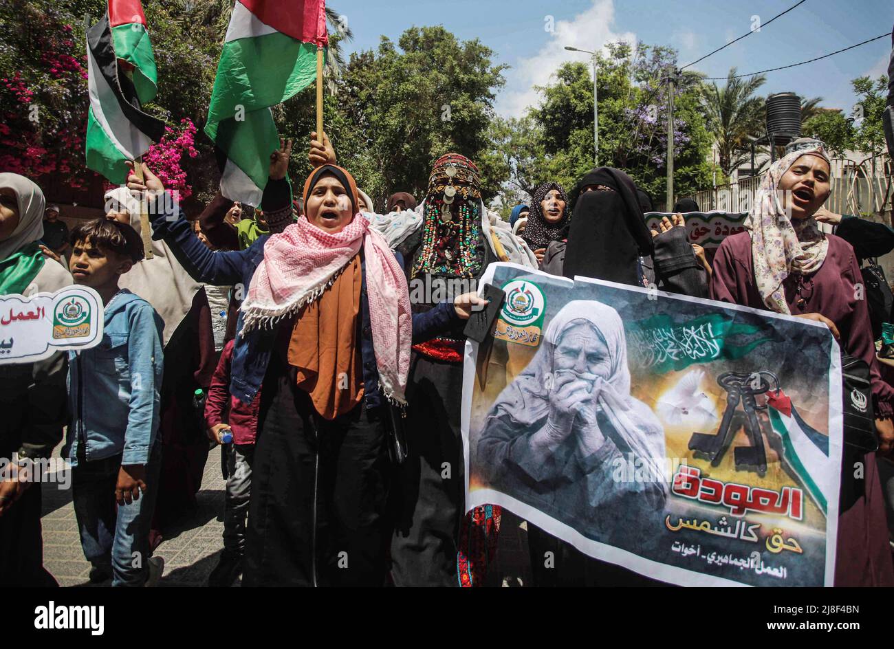 I palestinesi ondeggiano bandiere nazionali e tengono una bandiera mentre marciano durante un rally che segna il 74th anniversario della 'Nakba' o 'catastrofe', nella città di Gaza. I palestinesi e gli israeliani arabi a Gaza commemorano il 74th° anniversario della Nakba Day e condannano l'assassinio del giornalista palestinese-americano Shireen Abu Akleh da parte delle forze israeliane. Il termine 'Nakba? Significa 'catastrofe? In arabo e si riferisce alla pulizia etnica sistematica di due terzi della popolazione palestinese all'epoca da parte dei paramilitari sionisti tra il 1947-1949 e la distruzione quasi totale della società palestinese. (Foto b Foto Stock