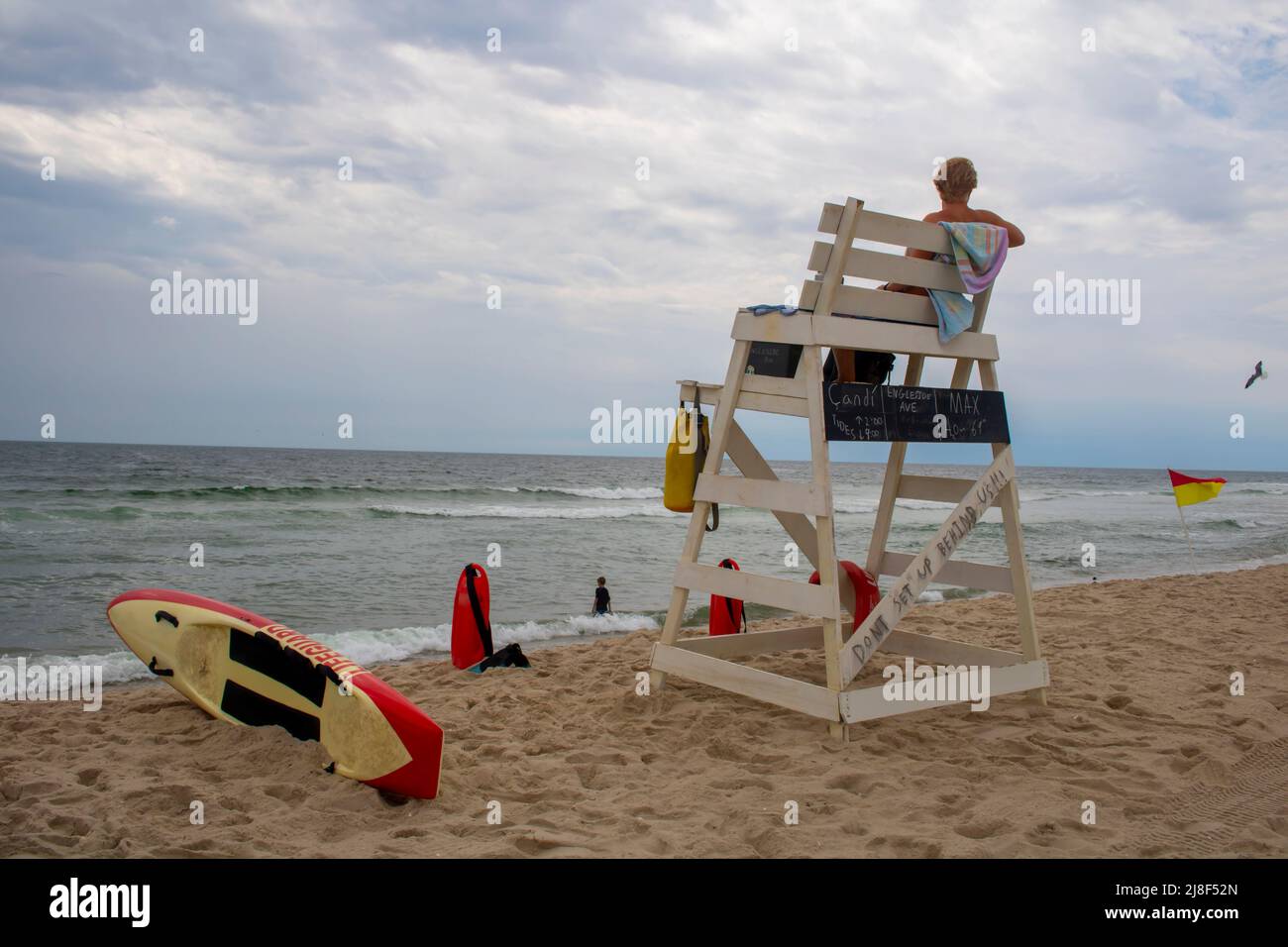 Spiaggia lifegard su una sedia alta lifegaurd che si affaccia e tenendo un occhio fuori nel mare dell'oceano Foto Stock