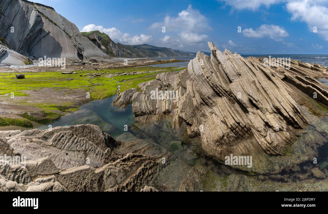 Una vista delle formazioni rocciose di Flysch e scogliere con piscine di marea sulla costa dei Paesi Baschi vicino a Zumaia Foto Stock