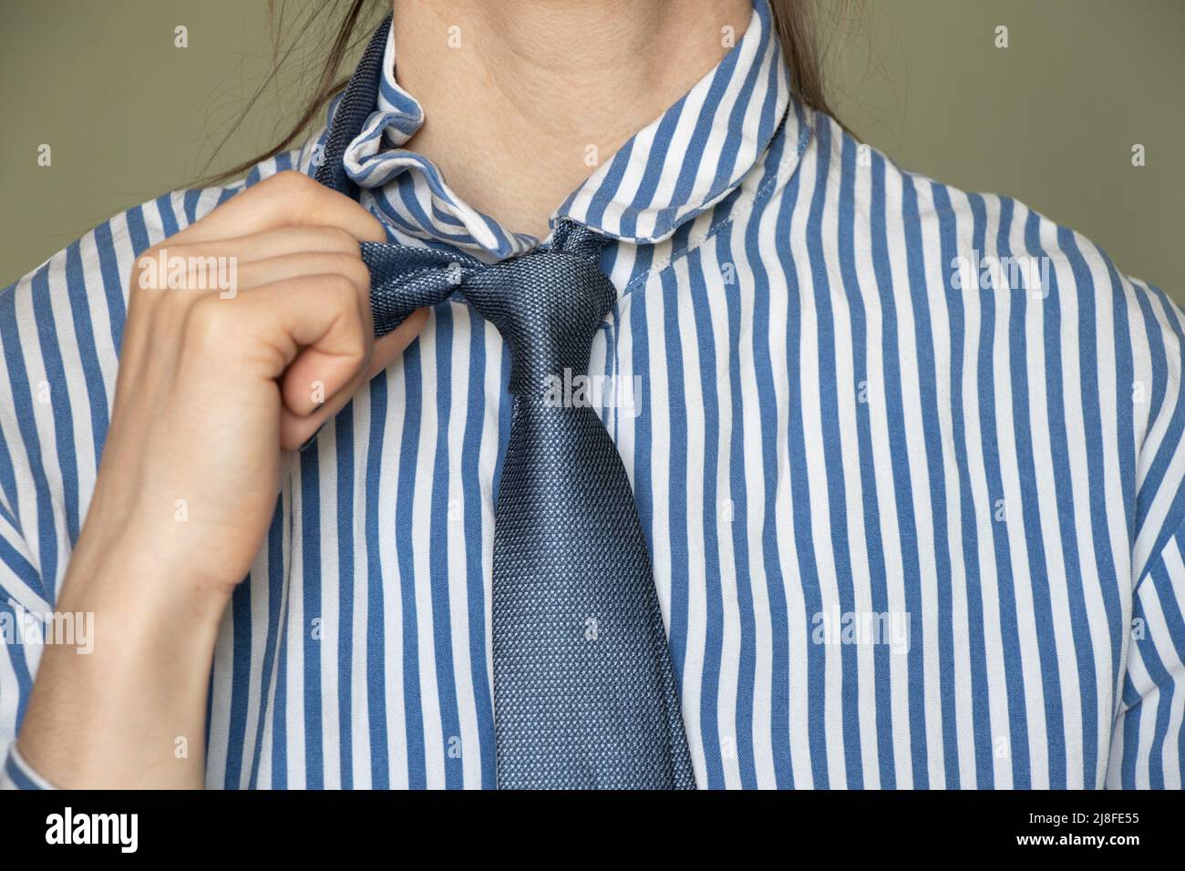 Primo piano di una giovane ragazza in una camicia a righe blu e cravatta,  abiti da lavoro, un lavoratore in ufficio in un vestito Foto stock - Alamy