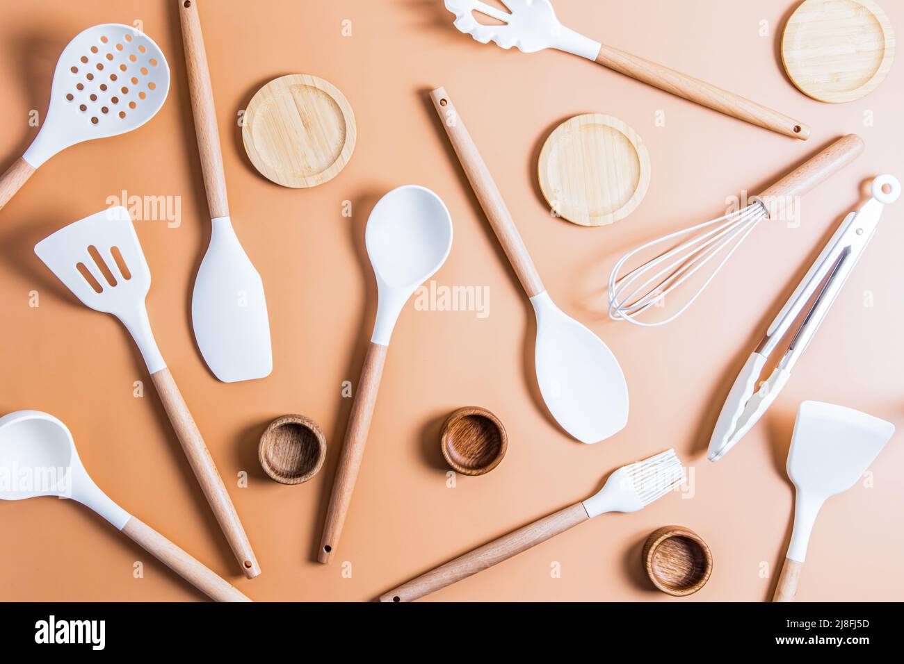 una collezione di utensili in silicone bianco per cucinare gli alimenti in cucina. vista dall'alto. styling piatto. sfondo beige Foto Stock