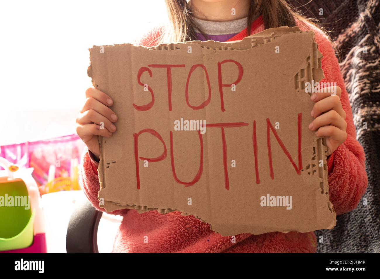 Una bambina tiene un poster con le parole fermare Putin a casa sua in Ucraina e chiede di fermare la guerra in Ucraina, i bambini chiedono, un'azione di protesta Foto Stock