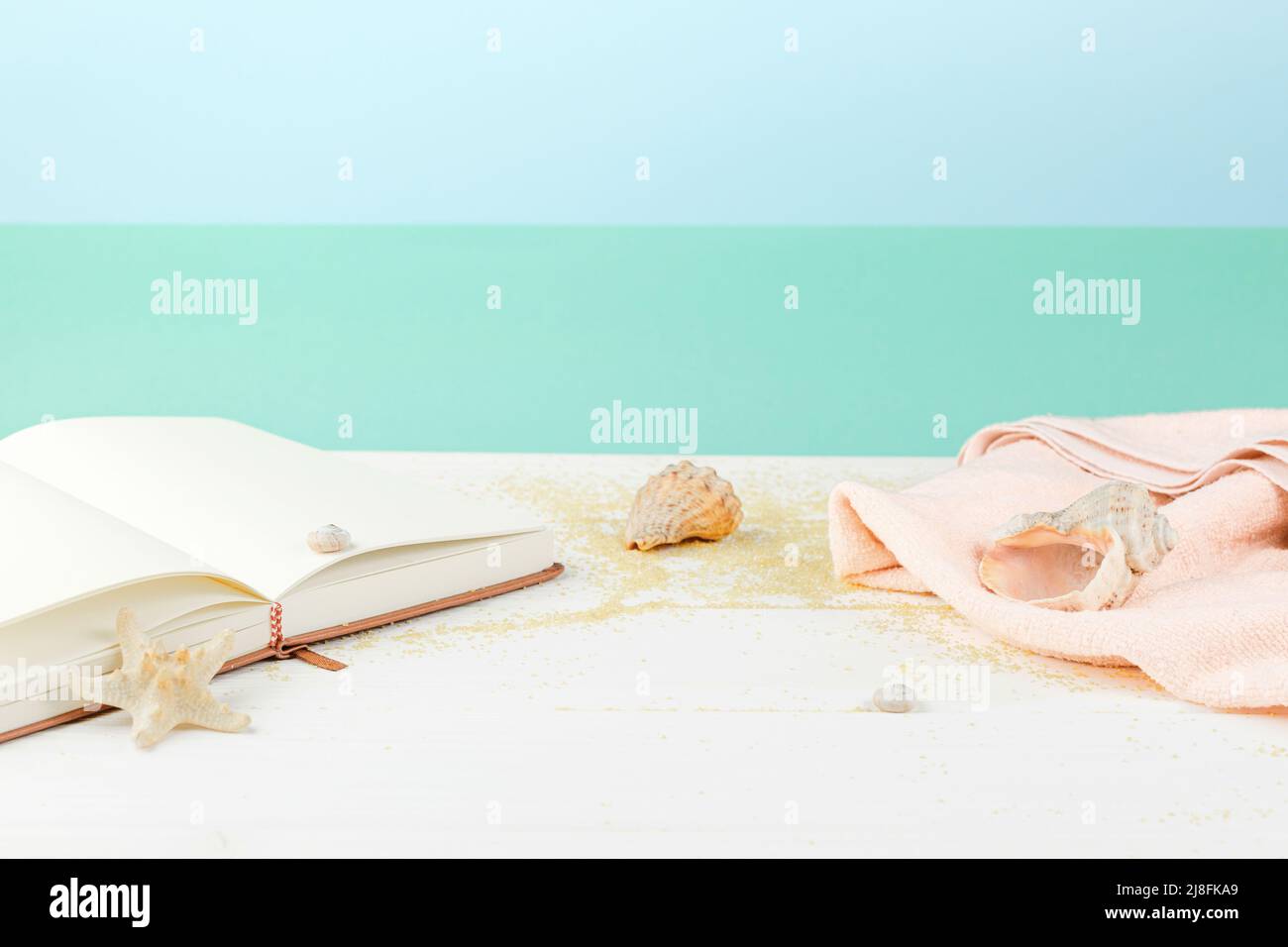Asciugamano con libro su tavolo di legno bianco Foto Stock