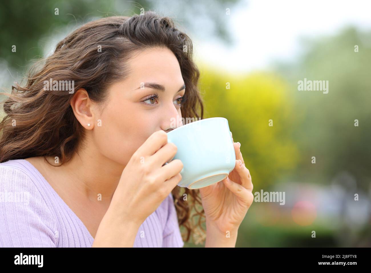 Bella donna che si rilassa bevendo caffè in un parco Foto Stock