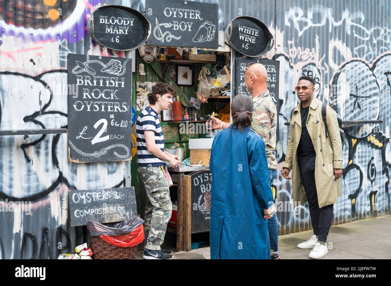 Negoziante e cliente in conversazione presso Oyster Boy, un punto vendita di ostriche "buco nel muro" a Ezra Street, Londra E2, Inghilterra, Regno Unito Foto Stock