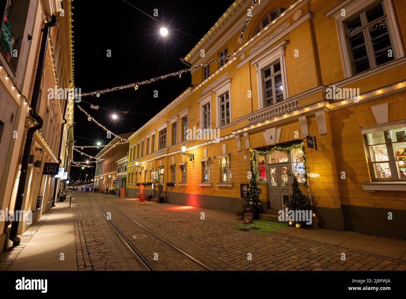 Vecchi edifici illuminati lungo la quasi vuota Katariinankatu strada presso l'idilliaco e storico Torikorttelit blocchi a Helsinki, Finlandia al tramonto nel mese di dicembre Foto Stock