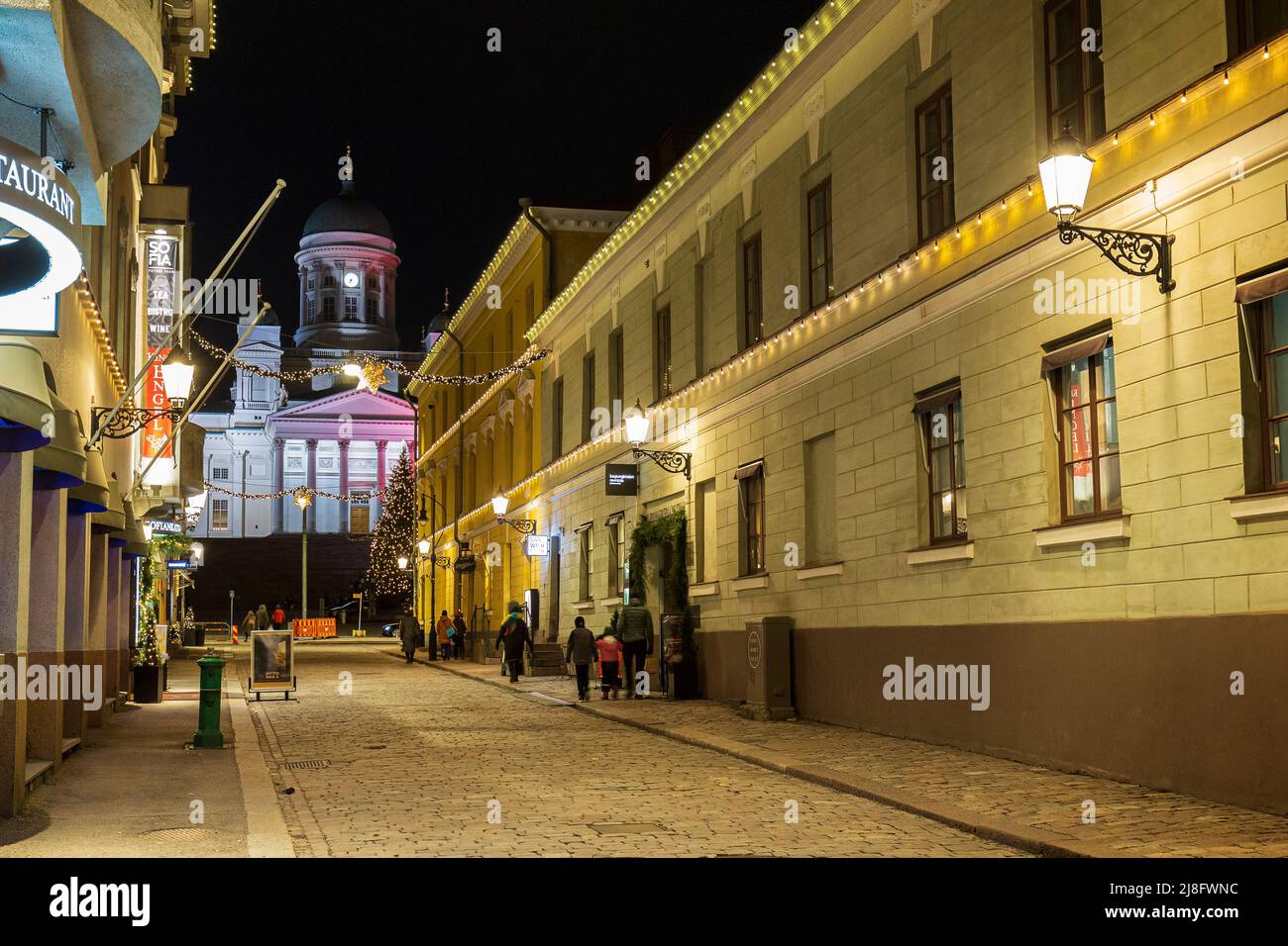 Vecchi edifici illuminati lungo la via Sofiankatu presso gli idilliaci e storici blocchi Torikorttelit e la Cattedrale di Helsinki a Helsinki, Finlandia al tramonto Foto Stock