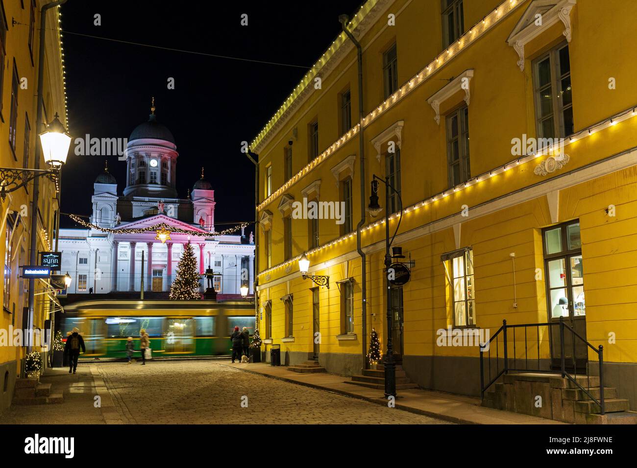 Vecchi edifici illuminati lungo la via Sofiankatu presso gli idilliaci e storici blocchi Torikorttelit e la Cattedrale di Helsinki a Helsinki, Finlandia al tramonto Foto Stock