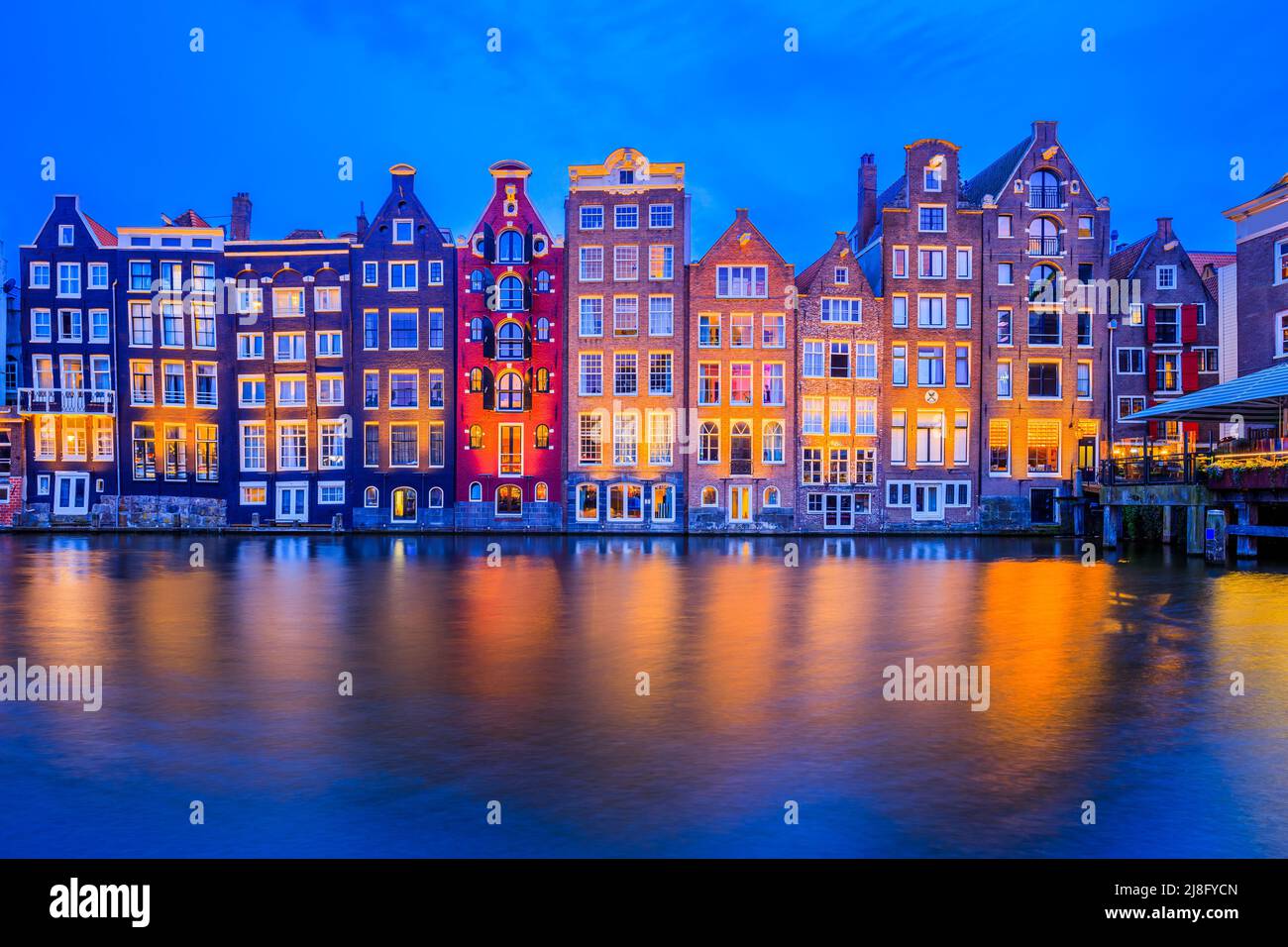 Amsterdam, Paesi Bassi. Case colorate sul canale Damrak. Foto Stock
