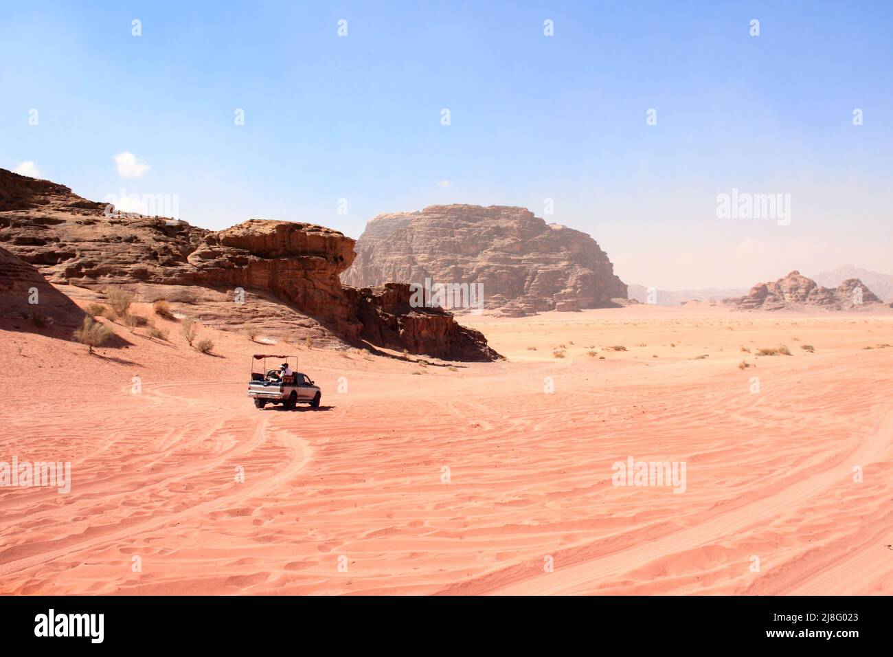 Safari in Jeep nel deserto di Wadi Rum, Giordania. I turisti in auto cavalcano sulla strada in fuoristrada sulla sabbia tra le splendide rocce. Paesaggio desertico con sabbia rossa e m roccioso Foto Stock