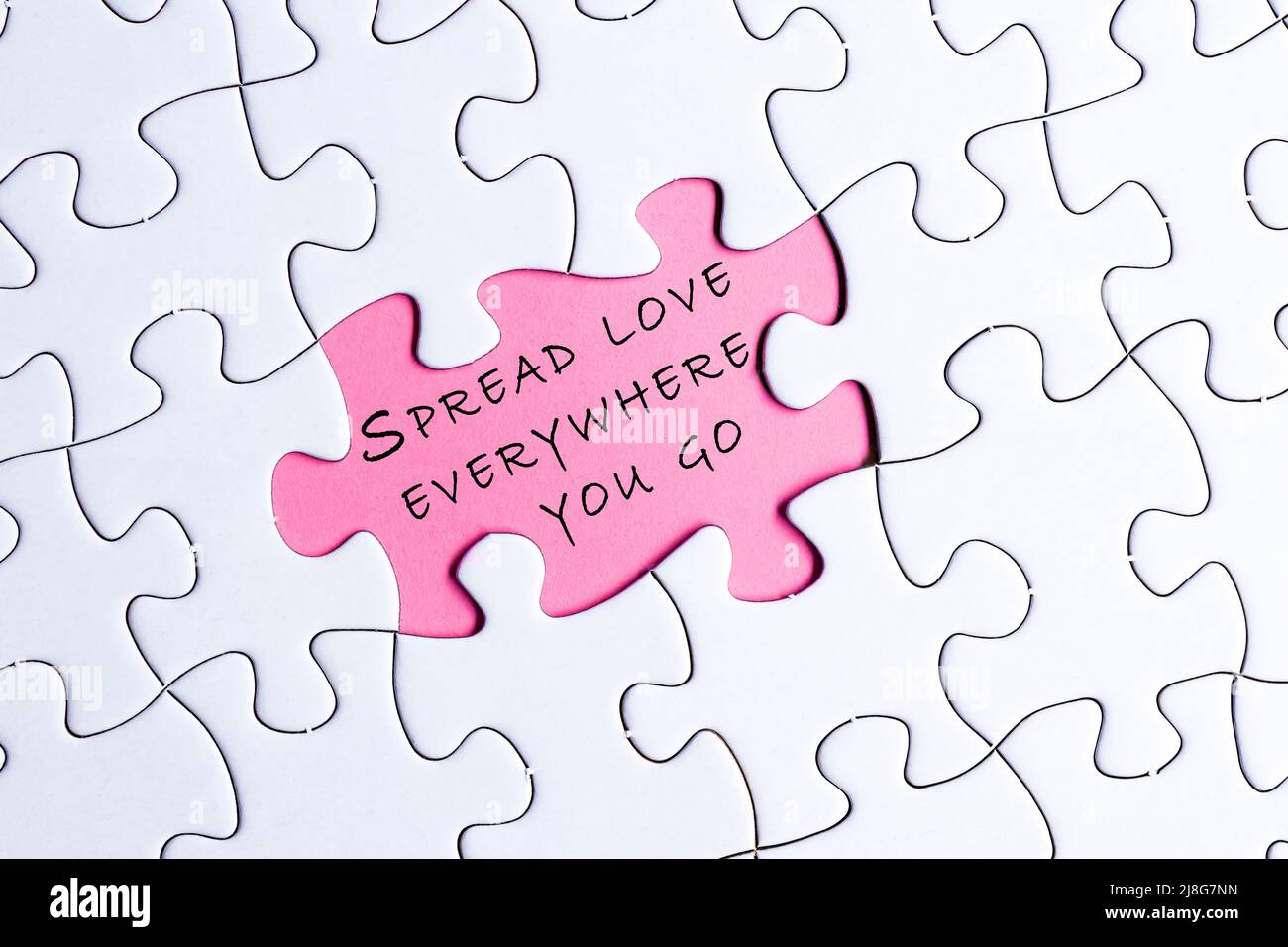 Puzzle bianco con citazione motivazionale e ispiratrice su sfondo viola - diffonde l'amore ovunque tu vada. Foto Stock