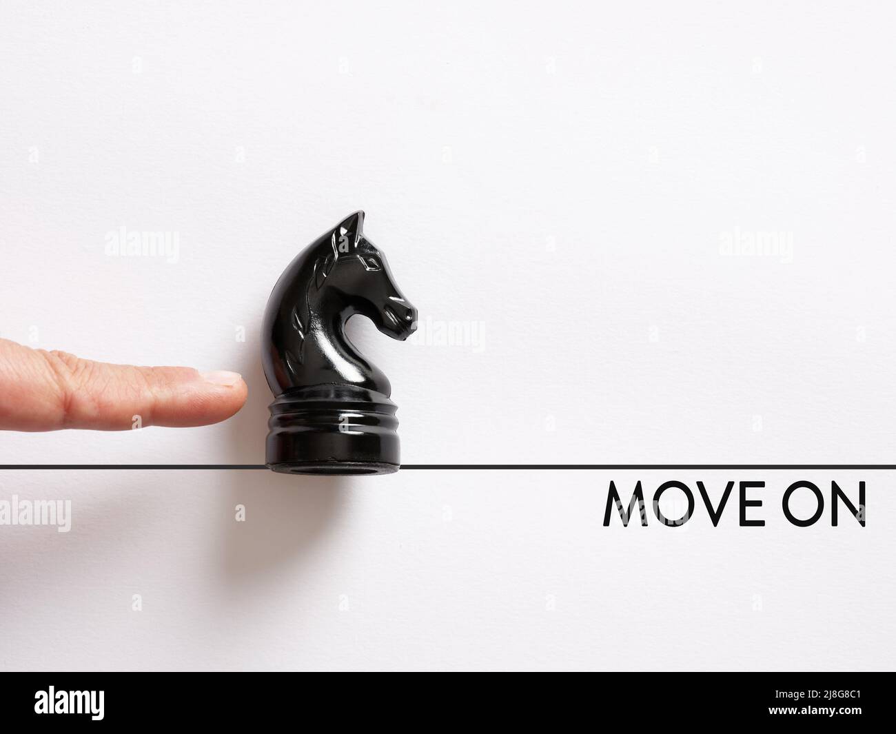 Il dito che spinge il cavaliere degli scacchi con il messaggio andare avanti. Agire, superare un ostacolo e passare al concetto. Foto Stock