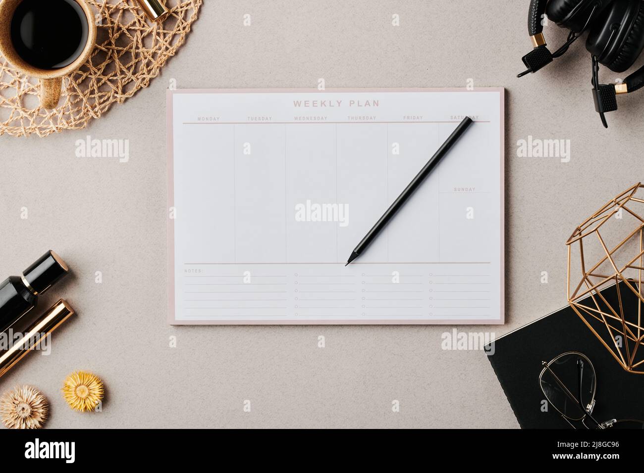 Flatlay di planner con matita circondata da tazza di caffè, copybook nero con occhiali e vasi fatti a mano e altri oggetti Foto Stock