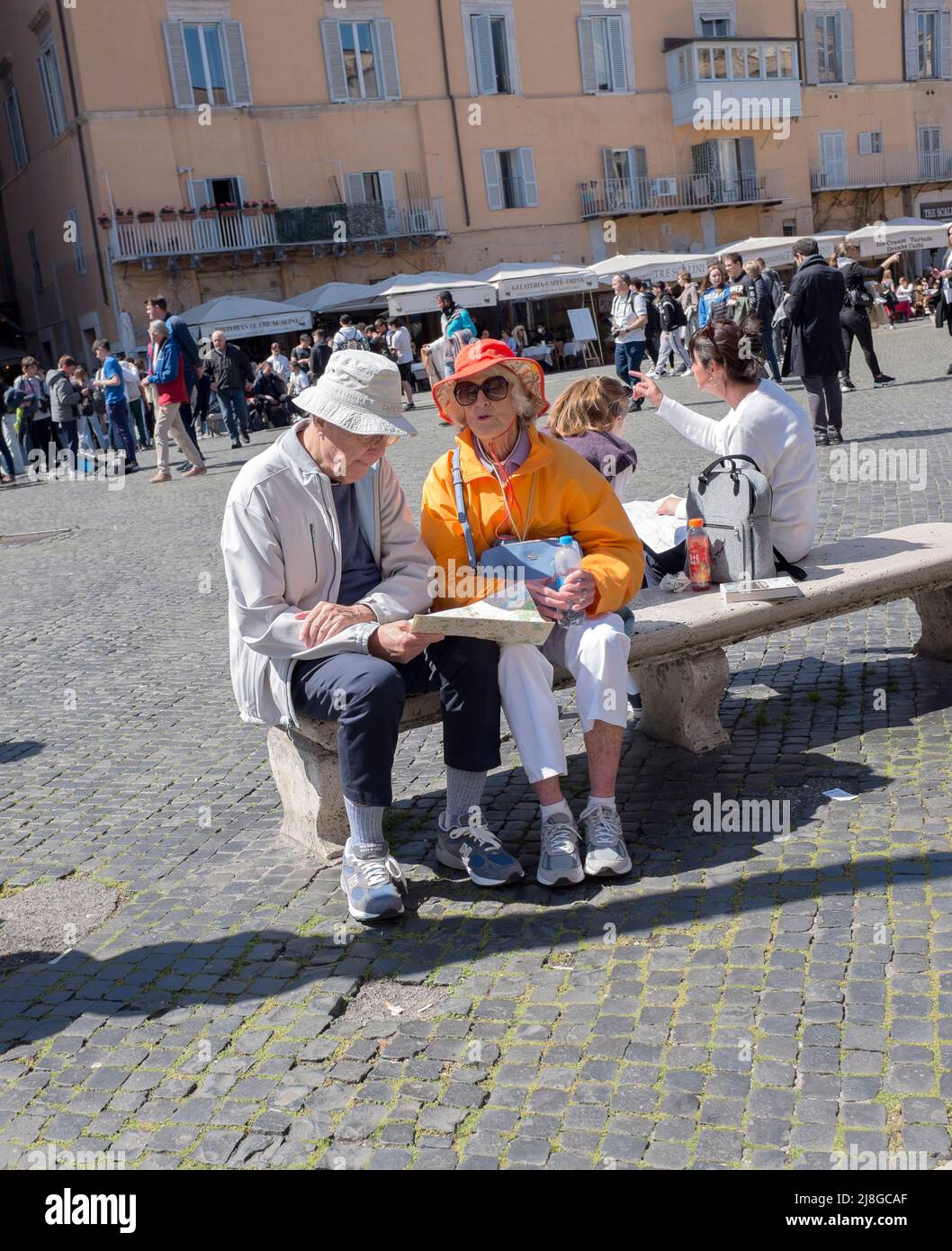 Mappa dei turisti maturi lettura seduta su una panchina in Piazza Navona Roma Italia Foto Stock