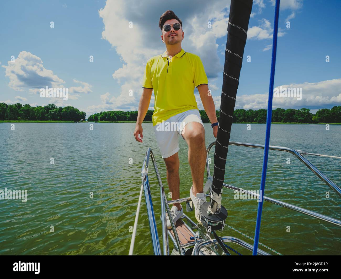 bella persona giovane capelli neri indossare abiti casual in piedi su una barca a vela prua e guardando davanti nella soleggiata giornata estiva Foto Stock