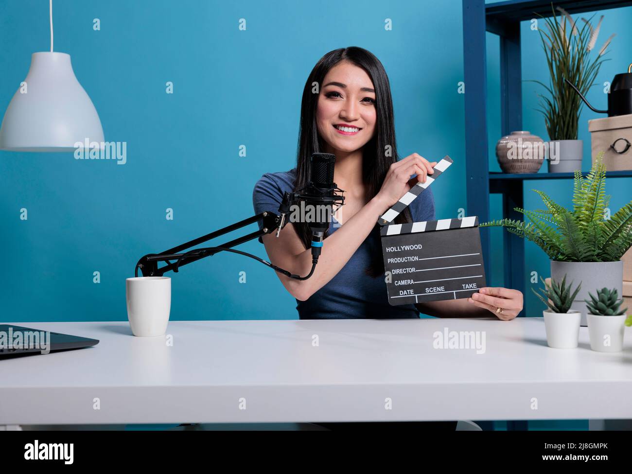 Il regista di film aggrappa l'ardesia davanti alla videocamera registrando il video-blog per il canale di vlogging utilizzando apparecchiature di produzione di streaming professionali. Recensione sulle riprese dei social media influencer Foto Stock
