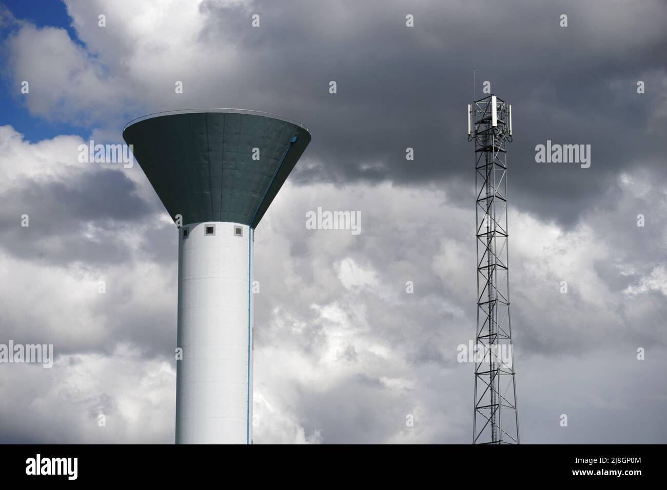 Torre dell'acqua vicino a un'antenna trasmittente per cellulari Foto Stock