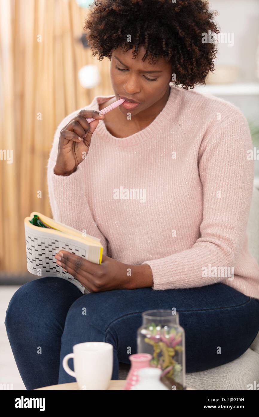 giovane donna nera che fa le cruciverba a casa Foto Stock