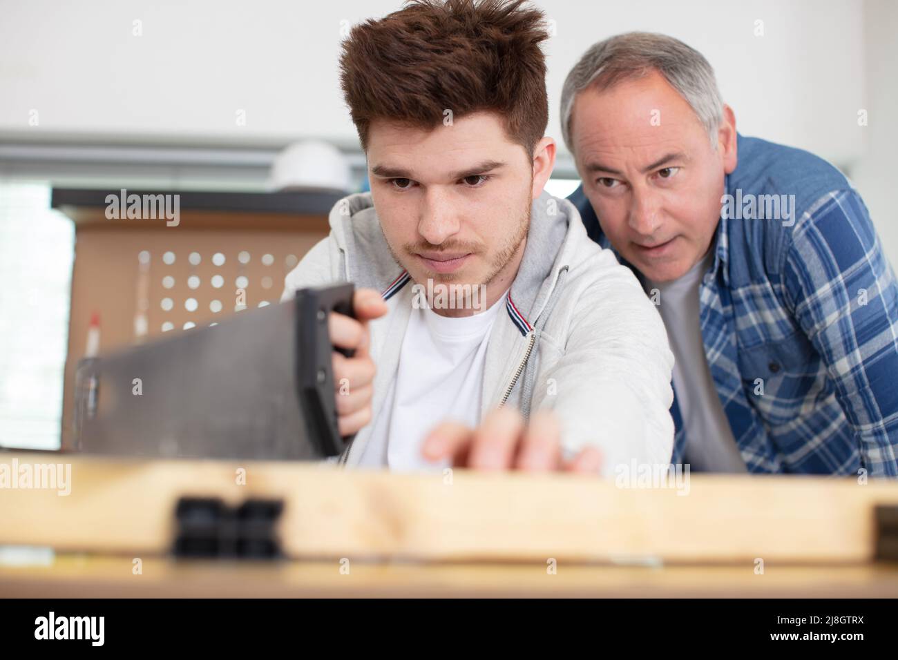 apprendista carpentiere utilizzando una sega sotto supervisione Foto Stock