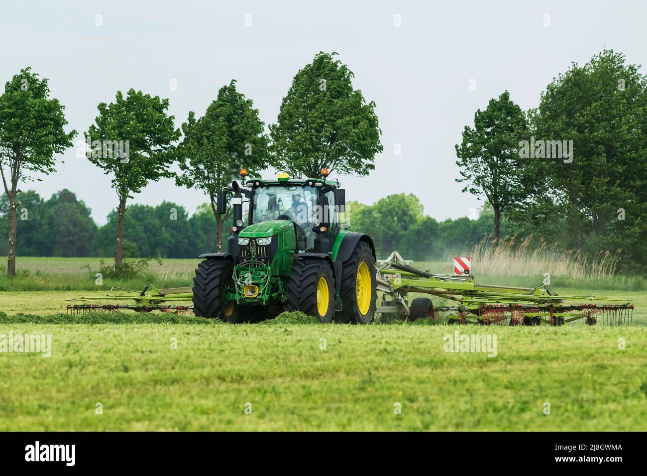 Un trattore con voltafieno in funzione Foto Stock