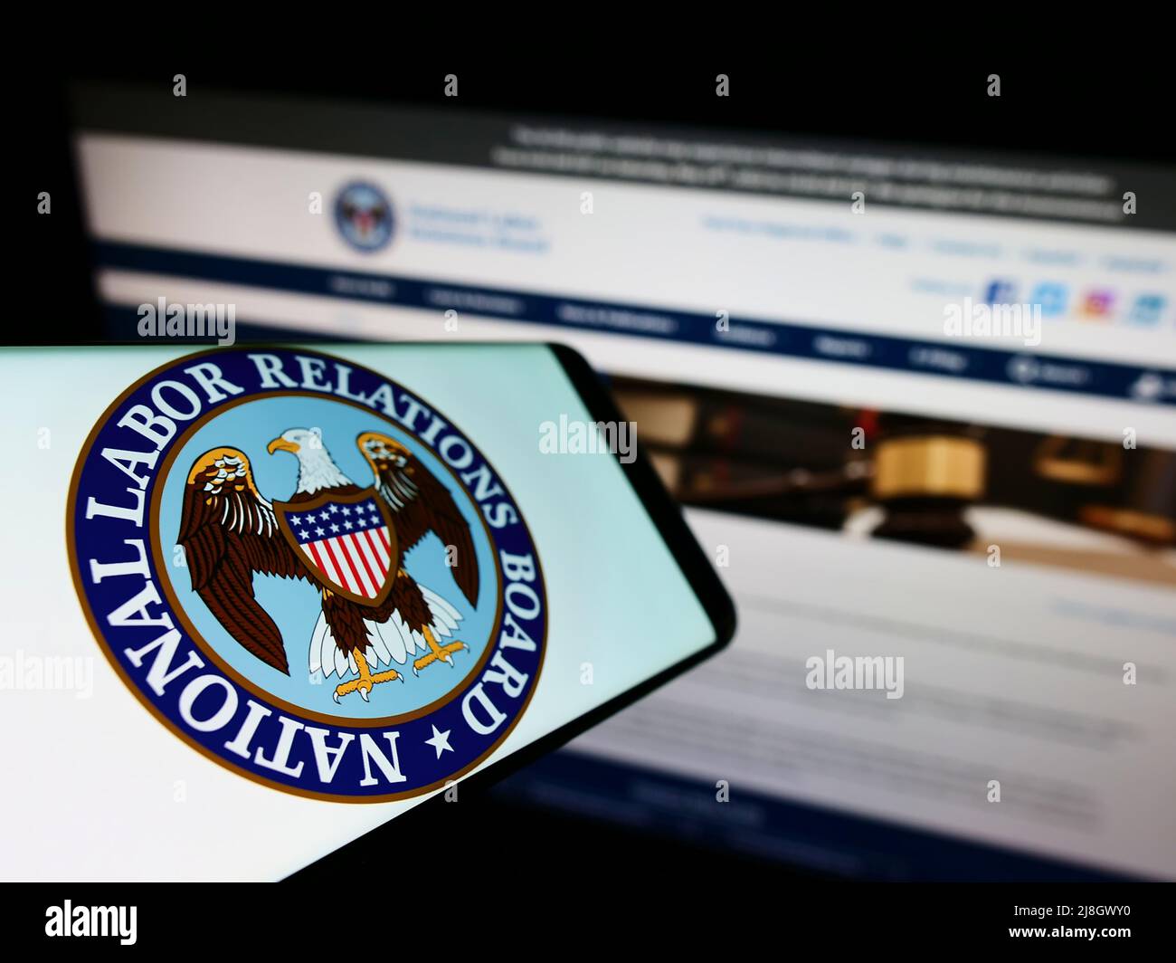 Telefono cellulare con logo dell'American National Labor Relations Board (NLRB) sullo schermo di fronte al sito web. Messa a fuoco al centro-sinistra del display del telefono. Foto Stock