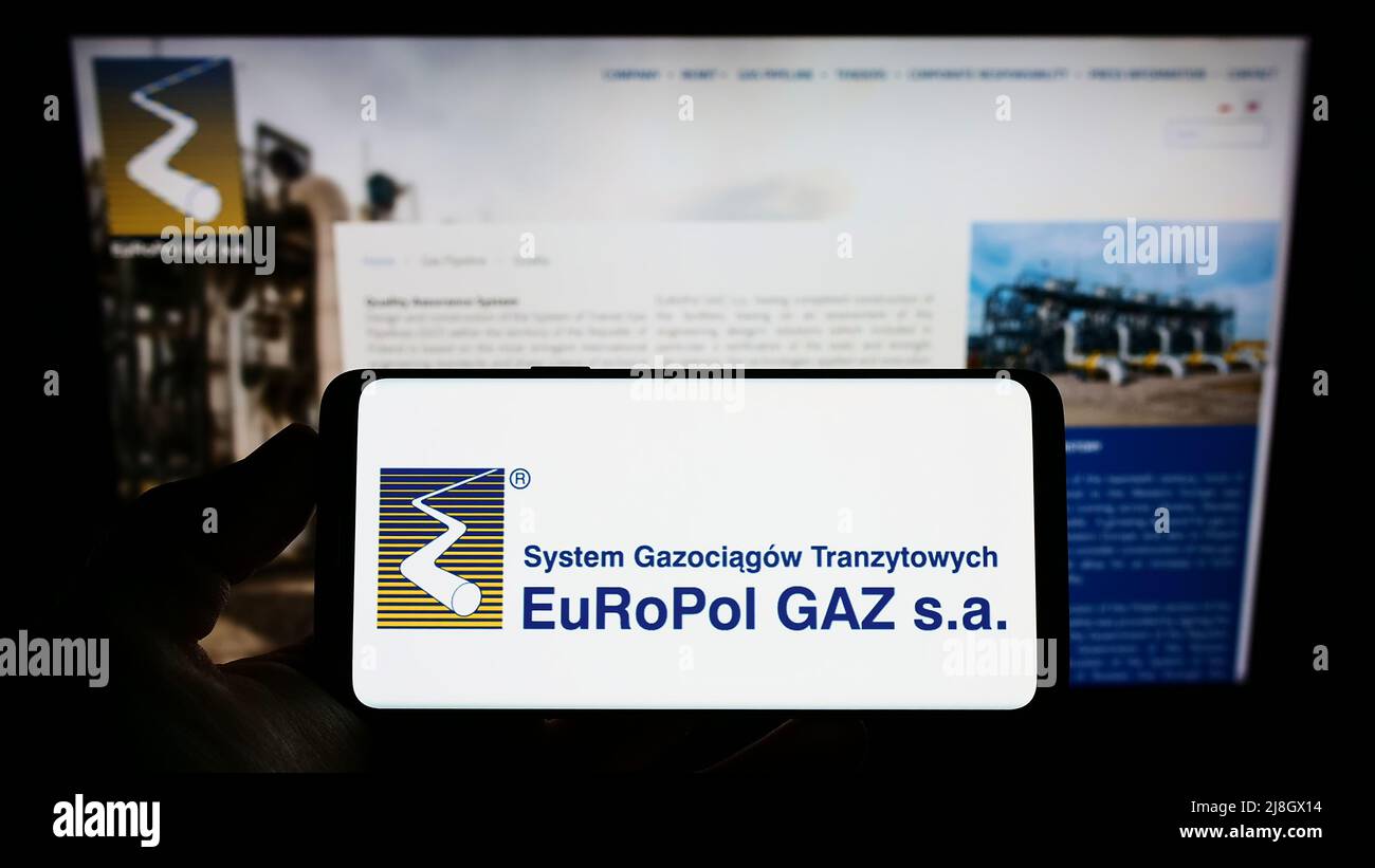 Persona che tiene uno smartphone con il logo della società di gas polacca Europol GAZ s.a. sullo schermo di fronte alla pagina web aziendale. Mettere a fuoco sul display del telefono. Foto Stock