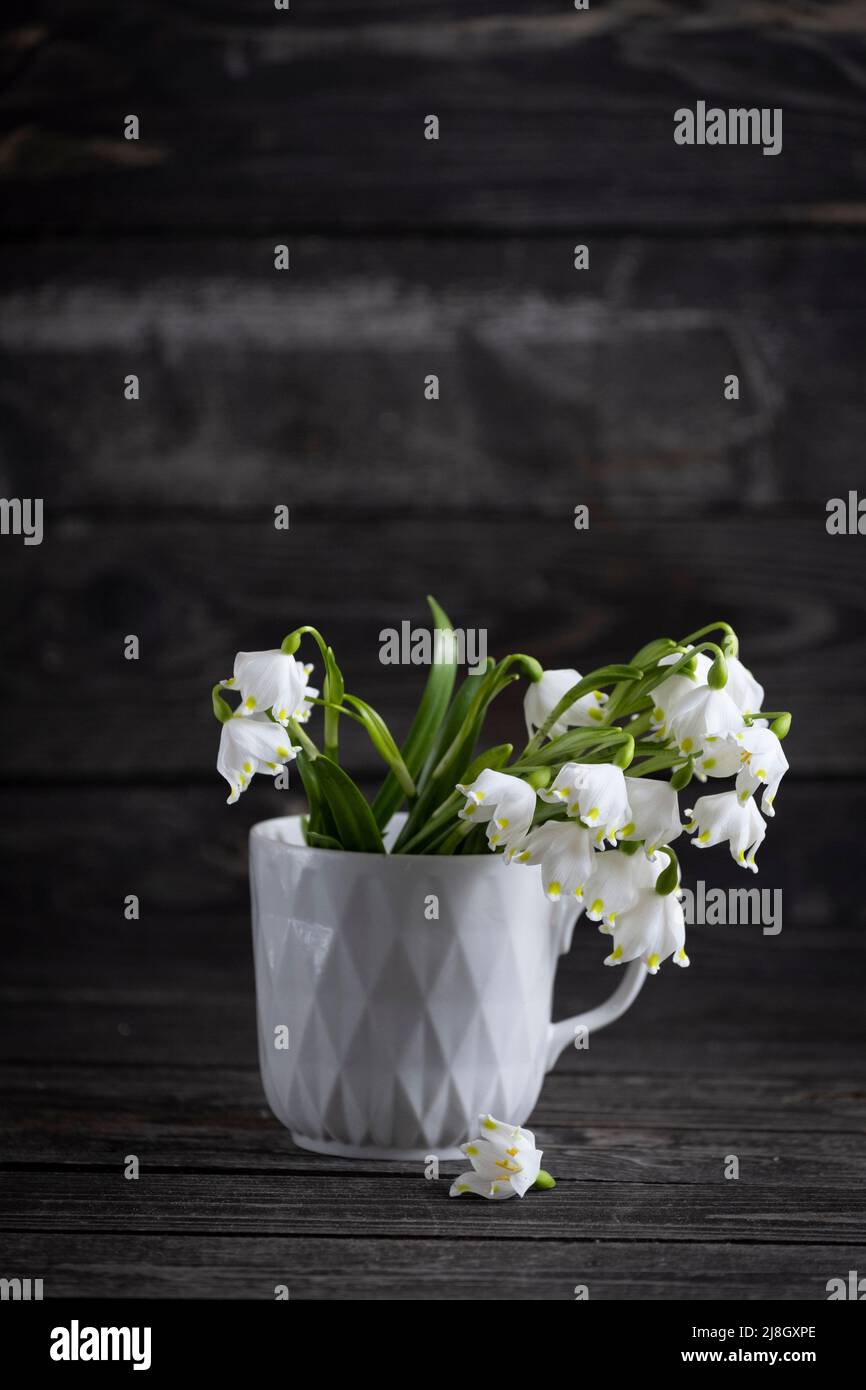 un mazzo di gocce bianche di primrose in vetro su sfondo di legno scuro Foto Stock