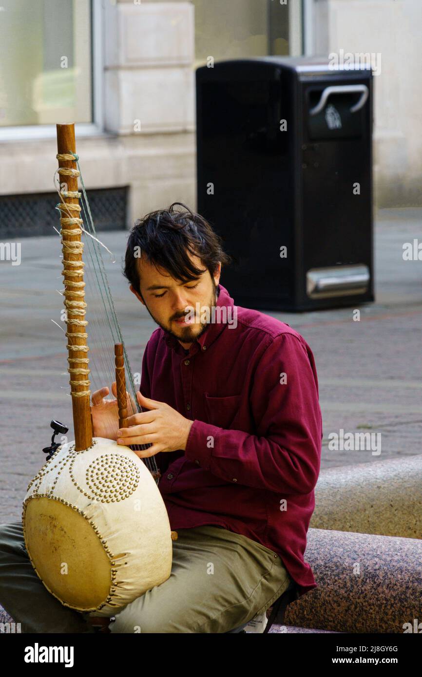 Una tradizionale arpa a 21 corde kora suonata da un musicista di strada con gli occhi chiusi nel centro di Manchester, Inghilterra, Regno Unito. Foto Stock